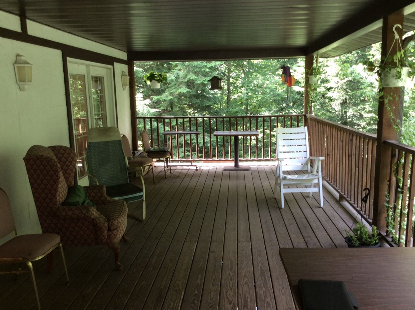 Wooden covered deck with seating overlooking the wooded grounds